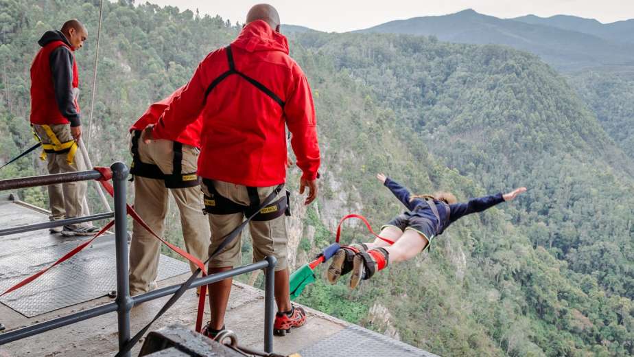 Face Adrenalin crew on the jump platform as a bungy jumper dives out over the Bloukrans gorge