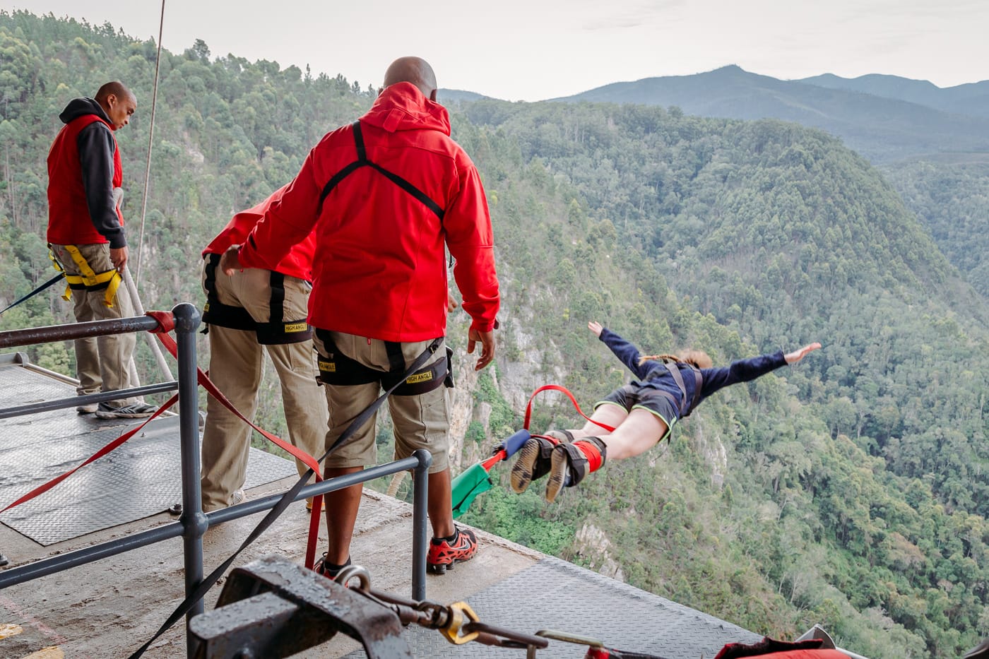 Face Adrenalin crew on the jump platform as a bungy jumper dives out over the Bloukrans gorge
