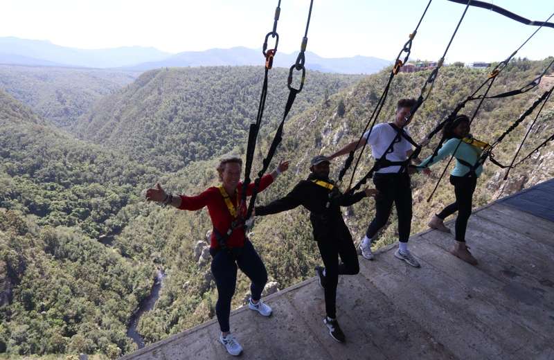 Visitors harnessed at the edge of Bloukrans Bridge, leaning out over the gorge at the Hangout