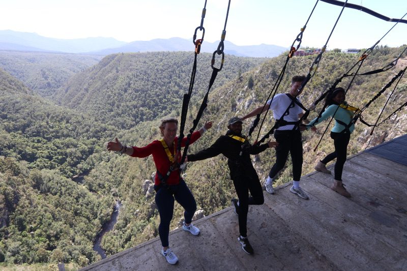 Visitors harnessed at the edge of Bloukrans Bridge, leaning out over the gorge at the Hangout